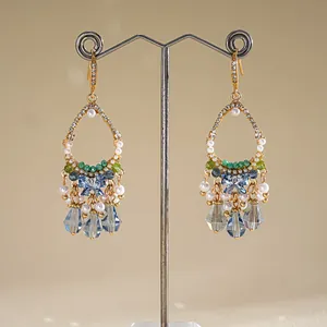 Détail de gros plan de boucles d'oreilles dorées avec cristaux bleus et perles blanches