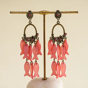 Détail de boucles d'oreilles pendantes en résine rose en forme de poisson vintage