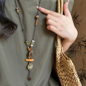 Vintage ethnic style long beaded necklace with moon pendant on olive dress background.