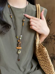 Detail of retro ethnic beaded necklace with moon and smiley face pendant on linen dress.