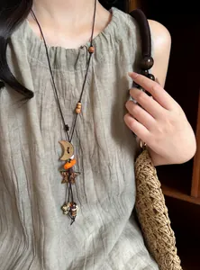 Detailed view of ethnic star and moon beaded necklace on a linen dress model.