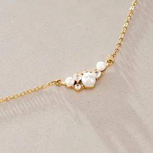 Primer plano detallado de un elegante collar de perlas doradas con circonitas brillantes