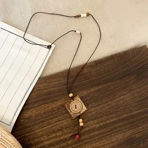 Detailed view of the handcrafted ethnic wooden pendant and beaded cord of the long necklace