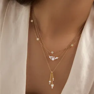 Vista detallada del collar dorado de tres capas con perlas y colgantes de circonita