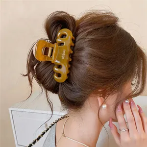 Close-up detail of a brown acrylic geometric hair claw clip styled in an elegant hair bun.