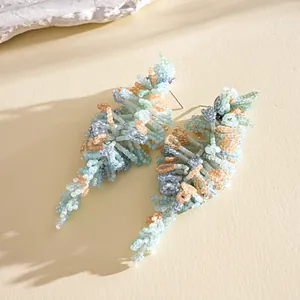 Gros plan de boucles d'oreilles à pompons en perles pastel, style bohème chic unique