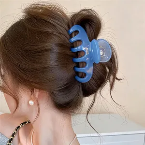 Elegant blue acrylic geometric hair claw clip shown worn in a bun hairstyle close-up view
