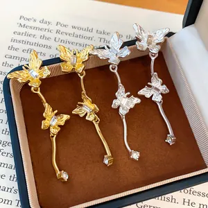 Gedetailleerd beeld van gouden en zilveren vlinder oorbellen in een geschenkdoos