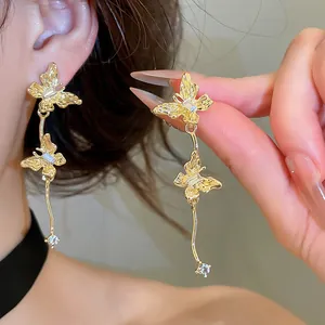 Detailopname van sprankelende gouden vlinderoorbellen met ingelegde kristallen.