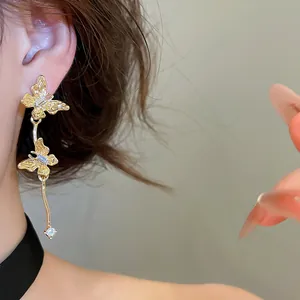 Gedetailleerde macro-opname van elegante gouden vlinder kwast oorbellen met strass-steentjes