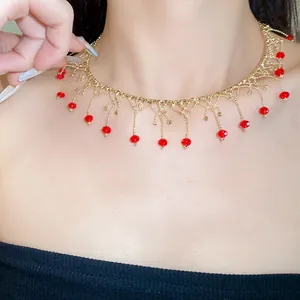 Close-up of elegant gold lace choker necklace featuring dangling red crystal beads