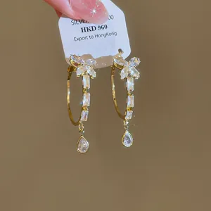 Detailopname van gouden oorringen met zirkonia vlinder en druppelvormige hangers