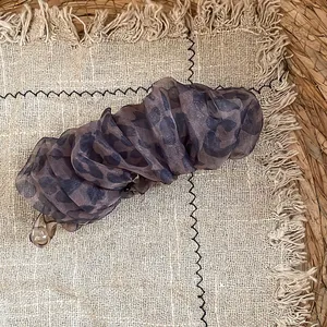 Detailansicht einer Vintage-Haarklammer mit Leopardenmuster und Faltennetz auf Leinenhintergrund.