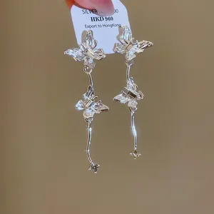 Detailopname van elegante zilveren vlinderkwastoorbellen met sprankelende kristallen