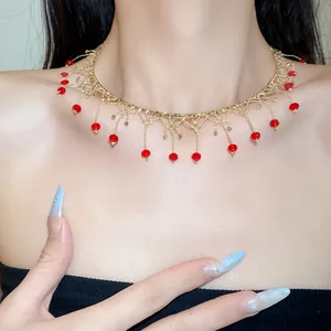 Detailed view of elegant gold lace choker necklace with red beaded tassels on model