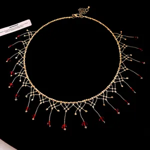 Detail view of a gold lace choker necklace featuring vibrant red crystal fringe drops.