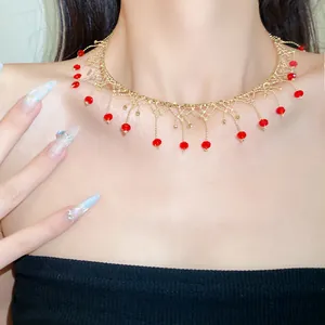 Detailed close-up view of gold lace choker featuring dangling red faceted beads on a model