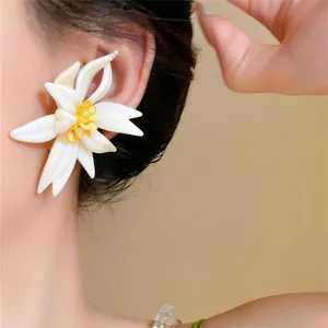Gros plan d'une boucle d'oreille fleur en cristal blanc portée à l'oreille