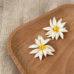 Vue macro d'exquises boucles d'oreilles fleurs blanches aux cœurs en cristal jaune