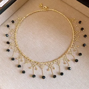 Close-up of gold beaded choker necklace with intricate black bead fringe detail.