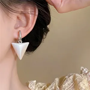 Close-up of elegant white pearlescent triangle drop earrings on an Asian model