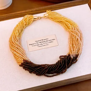 Elegante gelaagde kralenketting met goud en bruin kleurverloop in houten tray