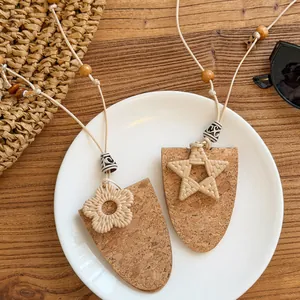 Vue détaillée des pendentifs étoile et fleur tissés sur collier en cuir de liège.