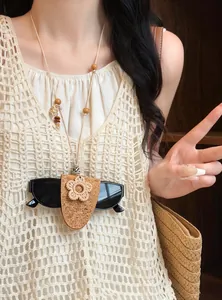 Handgemaakte boho leren ketting met geweven bloem die een zonnebril vasthoudt