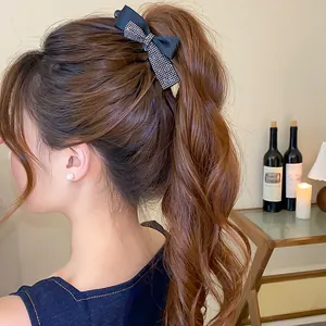 Vue détaillée d'une pince à cheveux nœud noir avec strass sur une queue de cheval haute