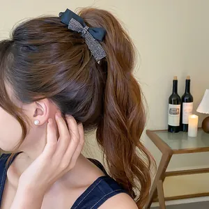 Gros plan d'une pince à cheveux nœud noir à strass portée sur une queue de cheval brune.