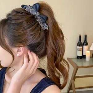Vue détaillée d'une élégante pince à cheveux nœud noir avec strass dans une queue de cheval