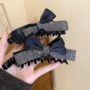 Gros plan de barrettes à nœud en satin noir élégant ornées de strass étincelants.