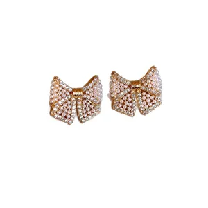 Elegante goldene Schleifen-Ohrstecker mit künstlichen Perlen und glitzernden Strasssteinen