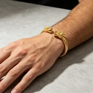 Detailansicht eines goldfarbenen Titanstahl-Armreifs mit Drachenkopf am Handgelenk