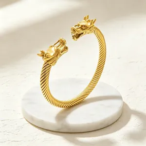Nahaufnahme eines goldenen Armreifs mit zwei Drachenköpfen und einer edlen, gedrehten Textur.