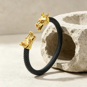 Detailaufnahme eines schwarzen Drahtseil-Armreifs mit zwei goldenen Drachenköpfen für Herren