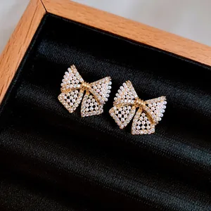 Nahaufnahme von eleganten goldenen Schleifenohrringen mit Perlen und Kristallen