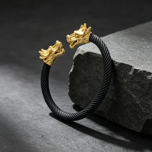 Detailansicht eines goldenen Doppeldrachen-Armreifs mit schwarzem gedrehtem Drahtseil-Design