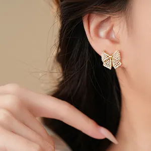 Elegante Schleifenohrringe mit Perlen und Kristallen im Detail an dem Ohr des Models