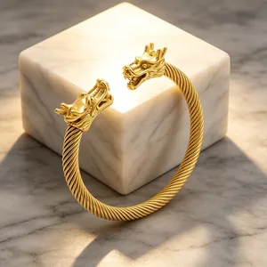 Detailaufnahme eines goldfarbenen Titanium-Stahl-Armreifs mit Doppelkopf-Drachen-Design.
