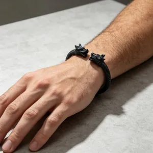 Detailansicht eines schwarzen Titanstahl-Armreifs mit doppeltem Drachenkopf am Handgelenk.