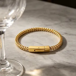 Detailed view of a gold stainless steel wheat chain bracelet with a square clasp on marble.