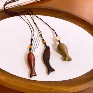 Detailopname van drie handgesneden houten vis hangers aan gevlochten koorden