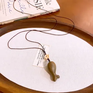 Gedetailleerde weergave van houten vis hanger ketting met bruin gevlochten koord
