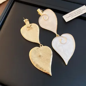 Detailansicht eleganter Tropfenohrringe aus weißem Emaille-Herz mit goldener Rückseite