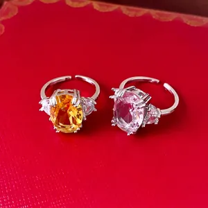 Eleganti anelli aperti in zircone con grandi pietre gialle e trasparenti su sfondo rosso