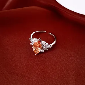 Luxe close-up van een zilveren ring met oranje zirkoon op rode stoffen achtergrond