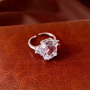 Close-up of elegant open ring featuring a large pink oval zircon and clear side stones.
