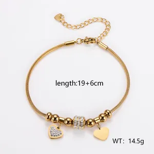Detailansicht eines 18k vergoldeten Schlangenkettchen-Armbands mit Herzanhängern und Steinen
