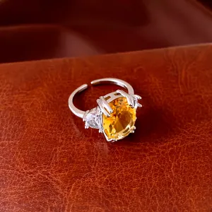 Detailed close-up of a silver open ring featuring a large oval yellow zircon centerpiece